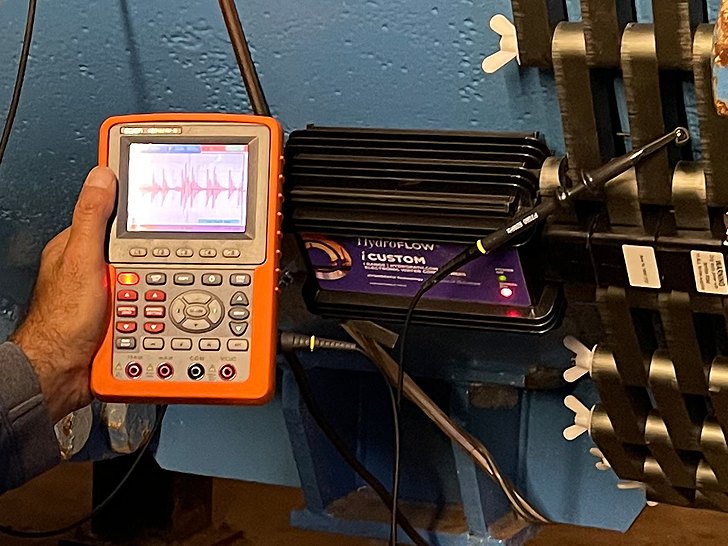Oscilloscope affichant le signal, relié à un appareil HydroFLOW posé sur un condenseur