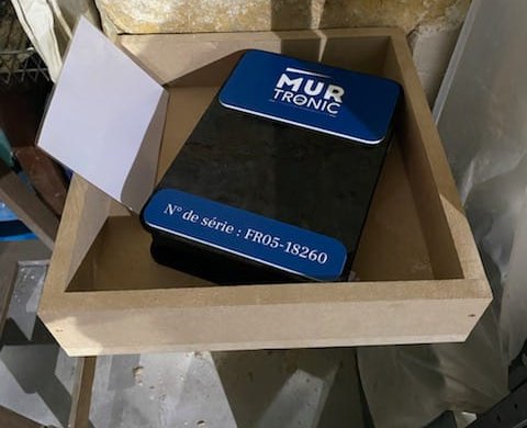 Boîtier Mur-Tronic posé à l'intérieur d'un local, contre un mur en pierre